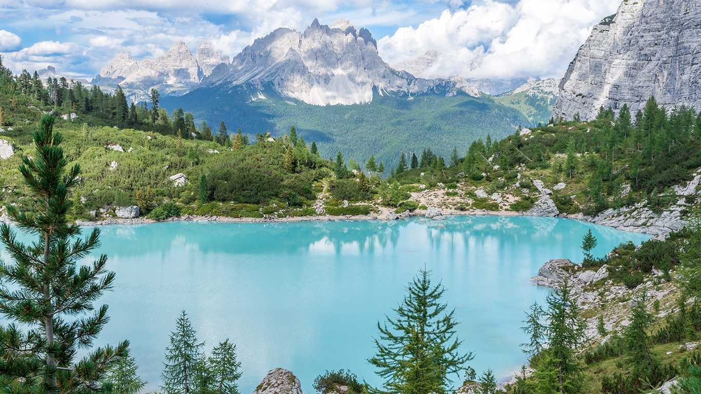 Um lindo lago de água azul, cercado por árvores e pedras